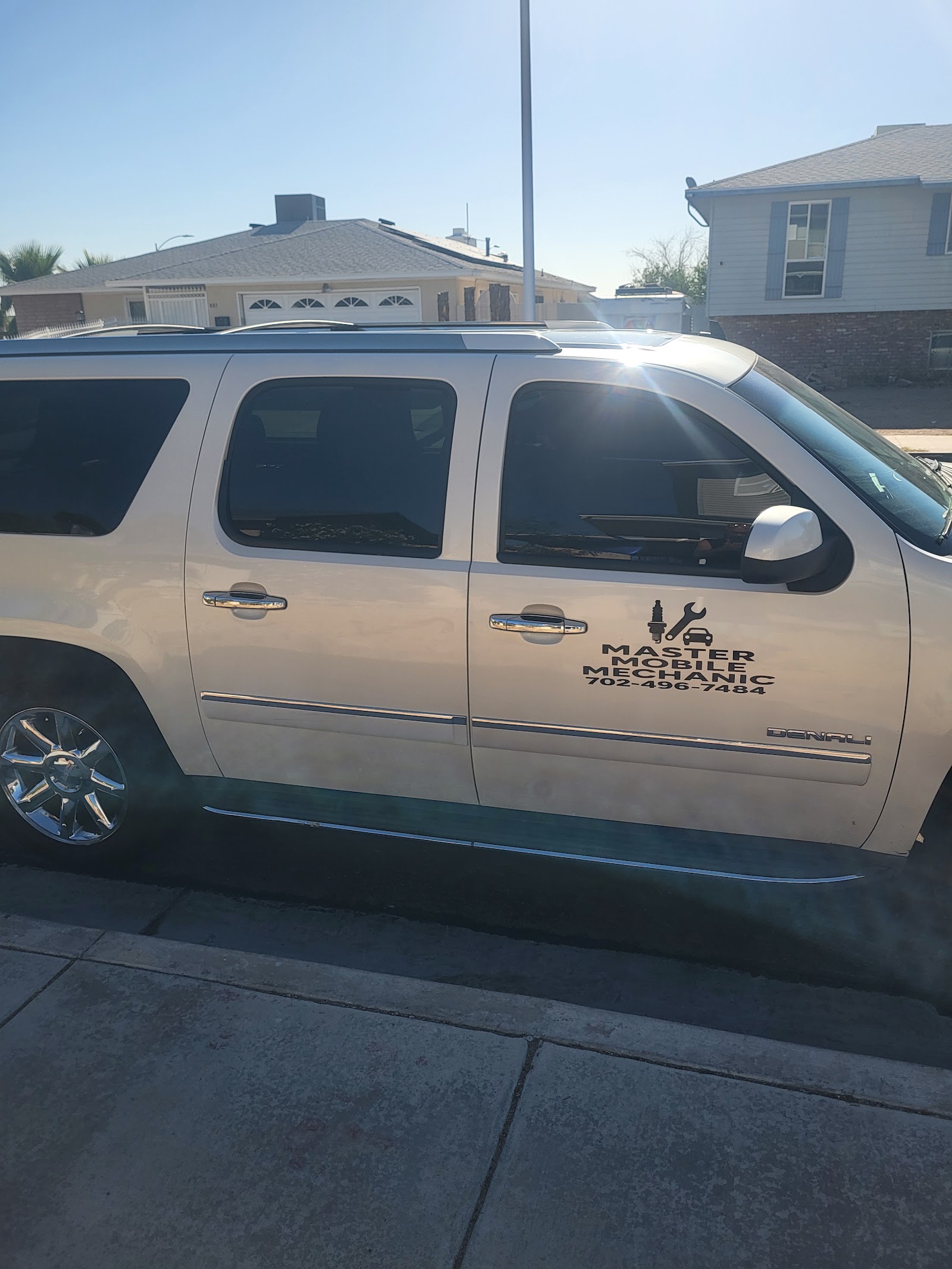 White GMC Denali SUV with a Master Mobile Mechanic 702-496-7484 door decal